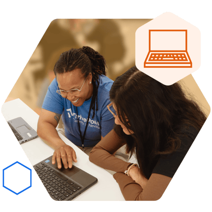 Teacher sitting with student at a desk with an open laptop