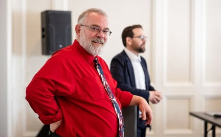 Staff member standing with his hand resting on the podium smiling at the camera