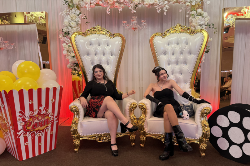 Students sitting down in big throne like white and gold chairs